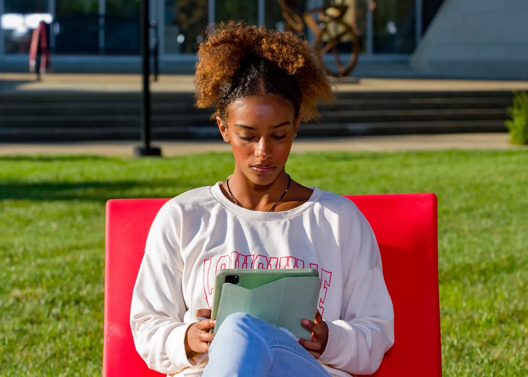 A student lounges in a chair in the 2020 Pavilion reading