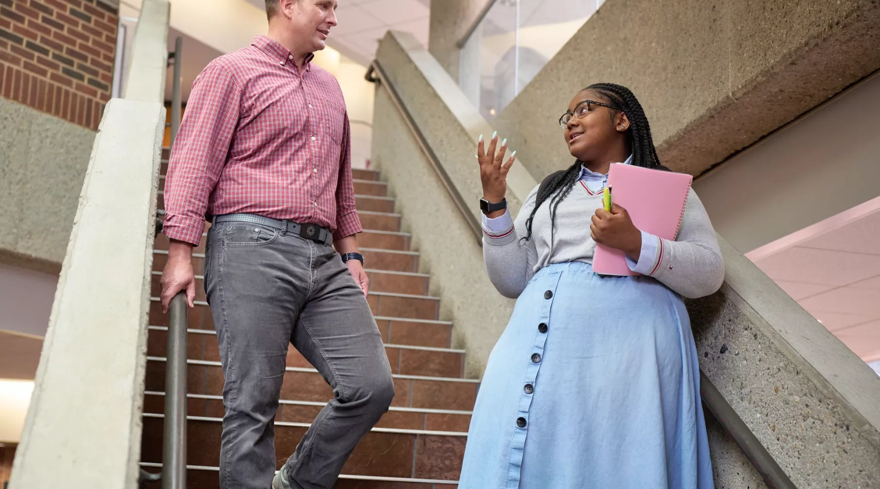 Two students talking at the stairs in the college of business.