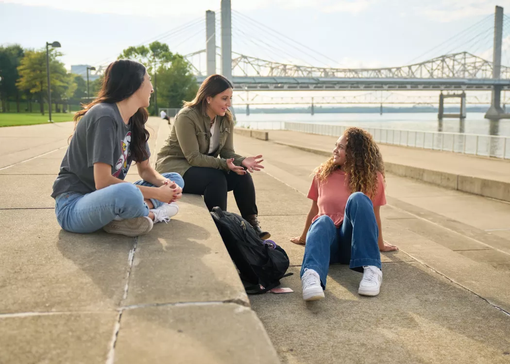 Three students talking on the steps at Waterfront Park in downtown Louisville.