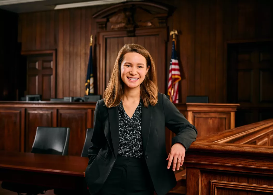 A young woman in a business suit stands in a mock courtroom