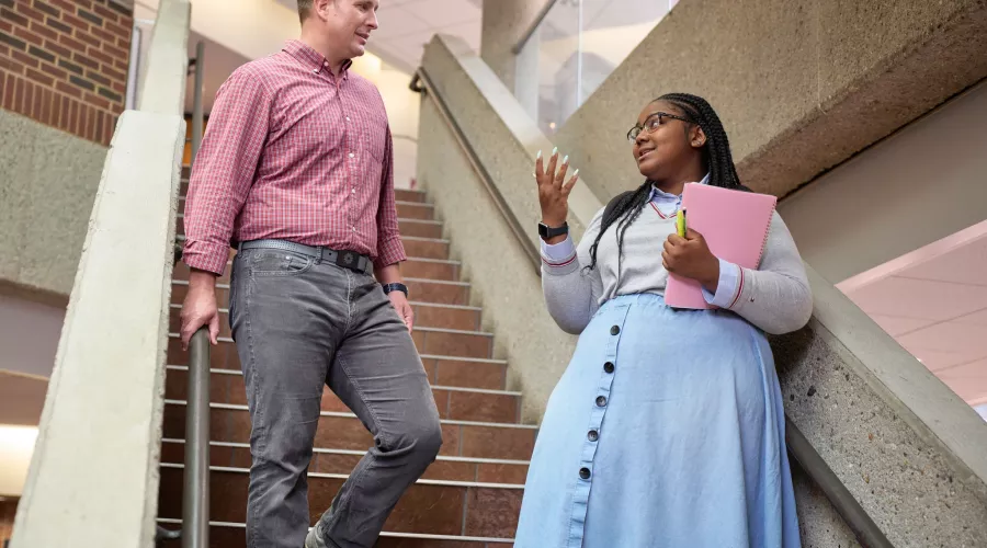 Two students talking at the stairs in the college of business.