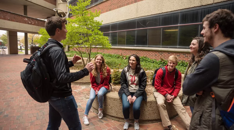 One student tells another group of students a story outside College of Business