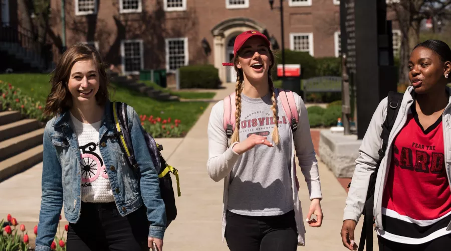 Three students laughing and walking near the School of Engineering
