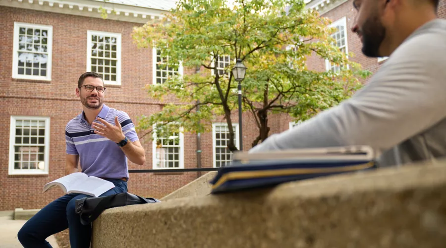 Two students having a socially distanced conversation in the courtyard at the Brandeis School of Law.